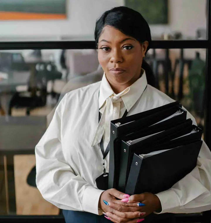 A woman in a white blouse holding a stack of black files