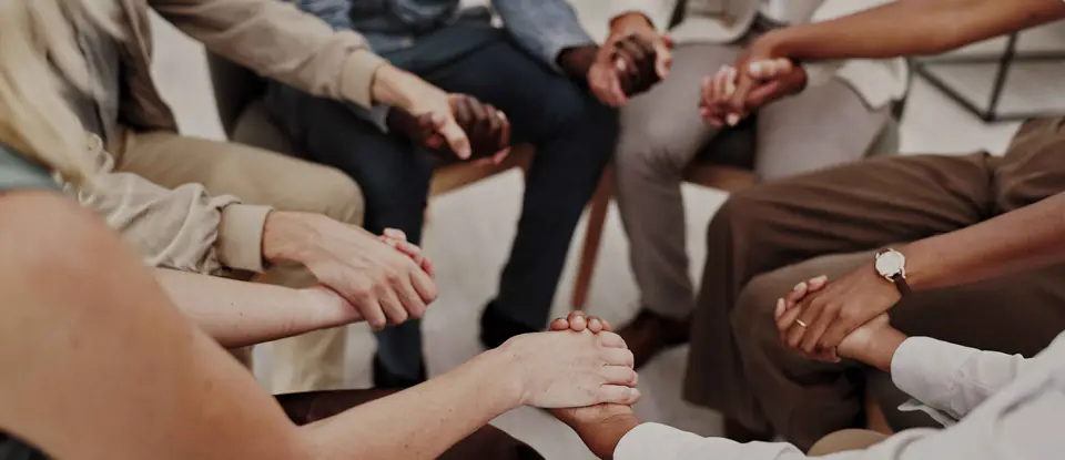 People sitting in a circle, holding hands