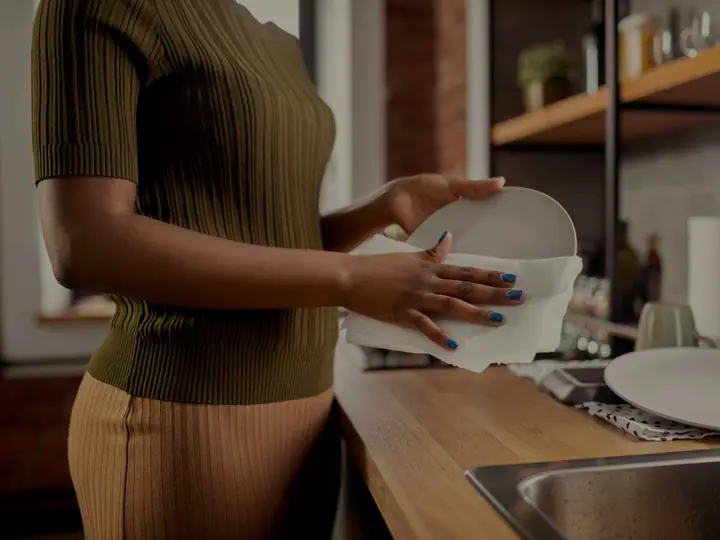 A woman drying a plate in her kitchen