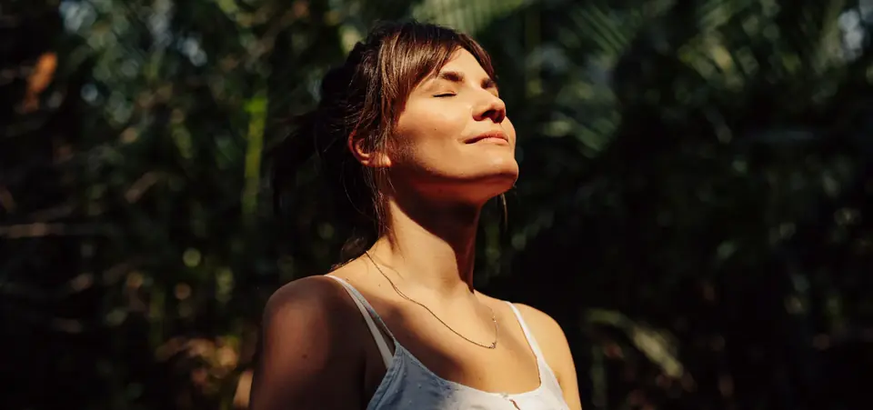 A woman with her eyes closed, her face turned towards the sunlight